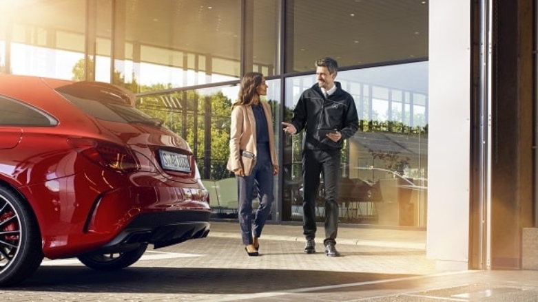 <p>Persona siendo atendida por servicio al cliente de Mercedes-Benz frente a concesionario automotriz.</p>