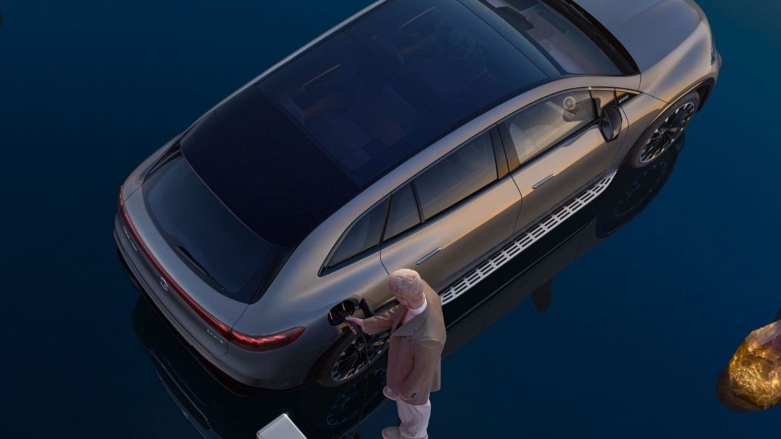 Persona cargando una SUV eléctrica Mercedes-Benz EQS.