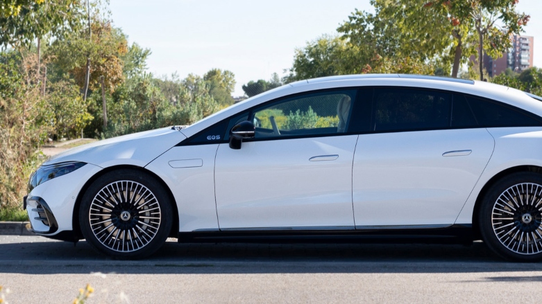 Vista lateral de carro eléctrico Mercedes-Benz EQS Sedan color blanco estacionada.